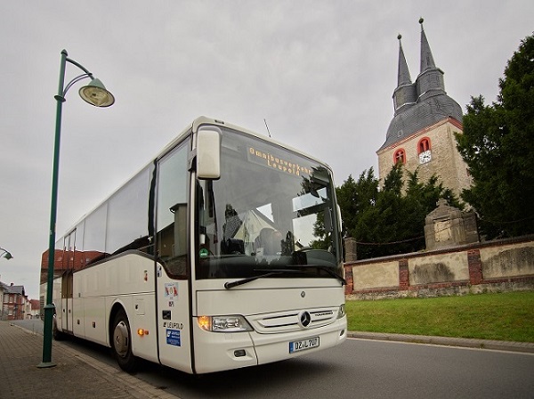 Bus steht an Haltestelle vor einer Kirche.